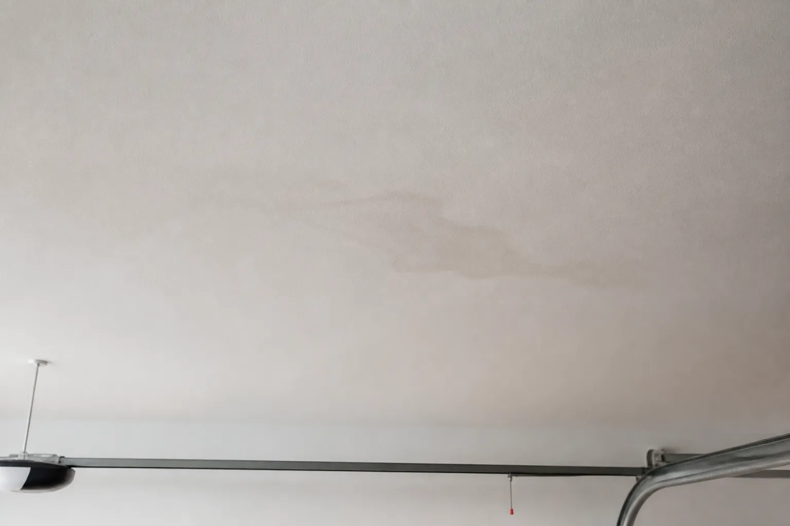 Teto de garagem residencial apresenta marca discreta de umidade.
