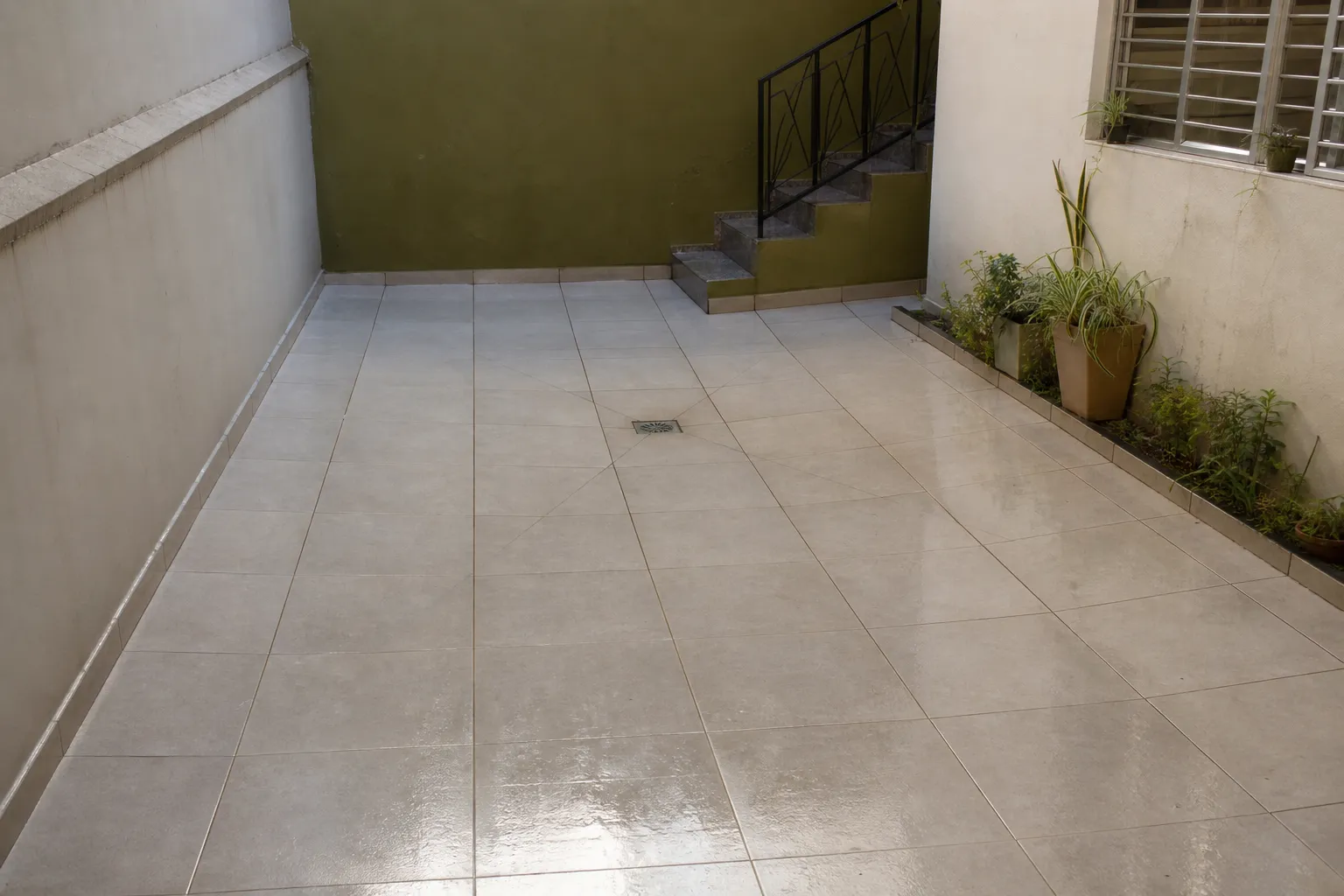 Piso de quintal com inclinação correta direcionando a água para o ralo central, facilitando o escoamento.