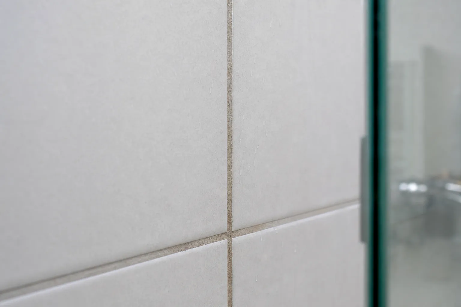 Rejunte escurecido entre azulejos claros de box de banheiro.