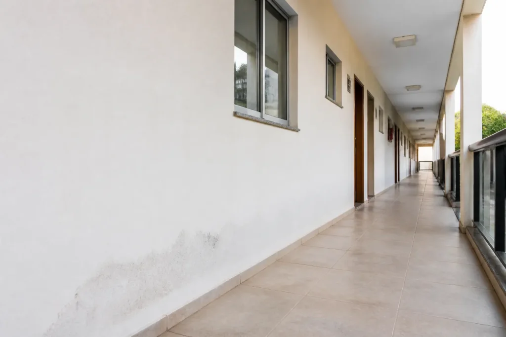Corredor de condomínio apresenta uma marca discreta de umidade.
