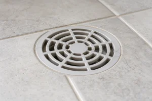 Fios de cabelo presos na grelha de ralo de banheiro limpo.