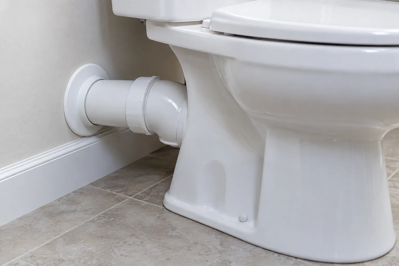 Conexão de PVC próxima a vaso sanitário novo em banheiro limpo.