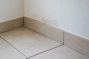 Umidade discreta no piso indica necessidade de investigar possível vazamento oculto.